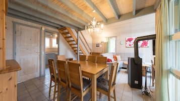 Un acogedor interior de cabaña con una mesa de comedor de madera, sillas, una escalera, un sofá y una chimenea.