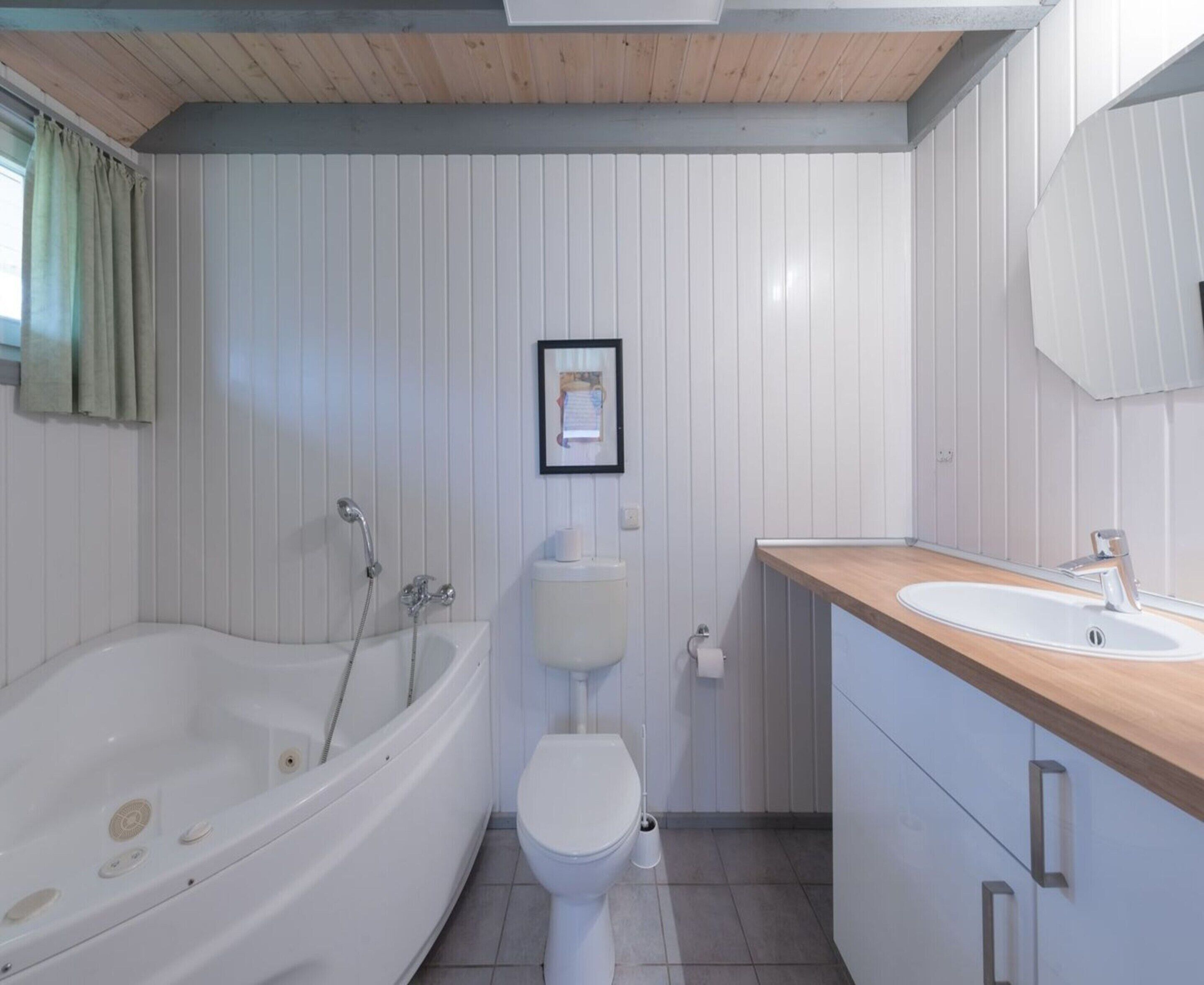 A bathroom with a bathtub, toilet, sink, and a framed picture on the wall.