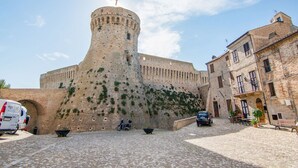 Eine historische Steinburg mit einem runden Turm, einem Kopfsteinpflasterhof und traditionellen Gebäuden.