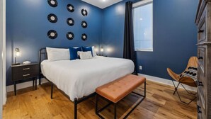 Une chambre à coucher comprenant un lit, des tables de chevet, un banc, une chaise et un mur décoré de motifs circulaires.