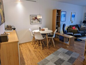 A modern living space with a dining area, a sofa, and a bookshelf.