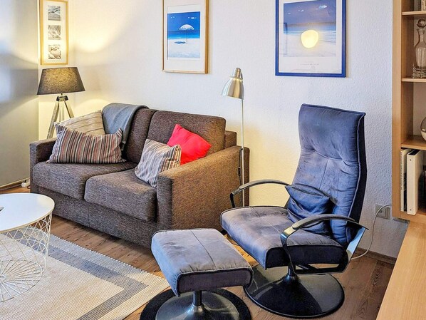 A living room with a sofa, a chair, a lamp, and framed pictures on the wall. - 4 Star Holiday Home in Neuschonberg (Schönberg)