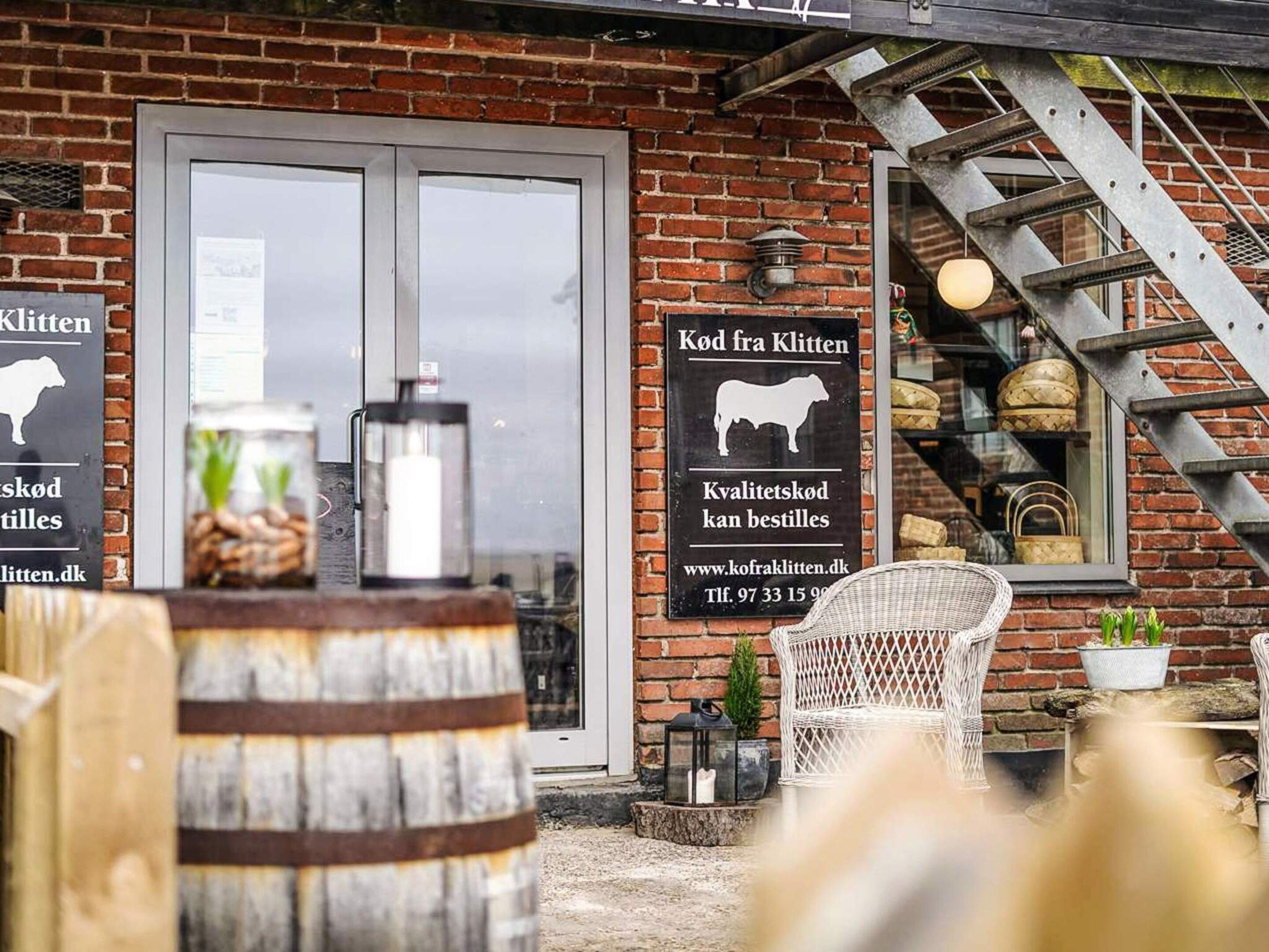 A brick building with a signboard, a wooden barrel, and a metal staircase.