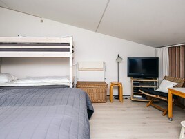Una habitación con literas, un escritorio con ordenador, televisión y lámpara.