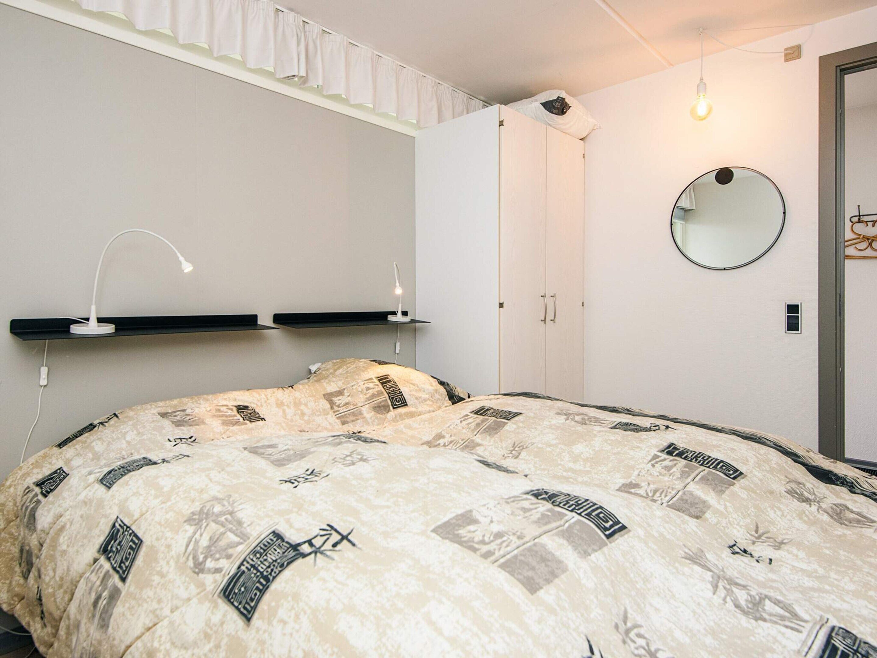 Une chambre à coucher comprenant un lit, une armoire, un miroir et deux lampes de chevet.
