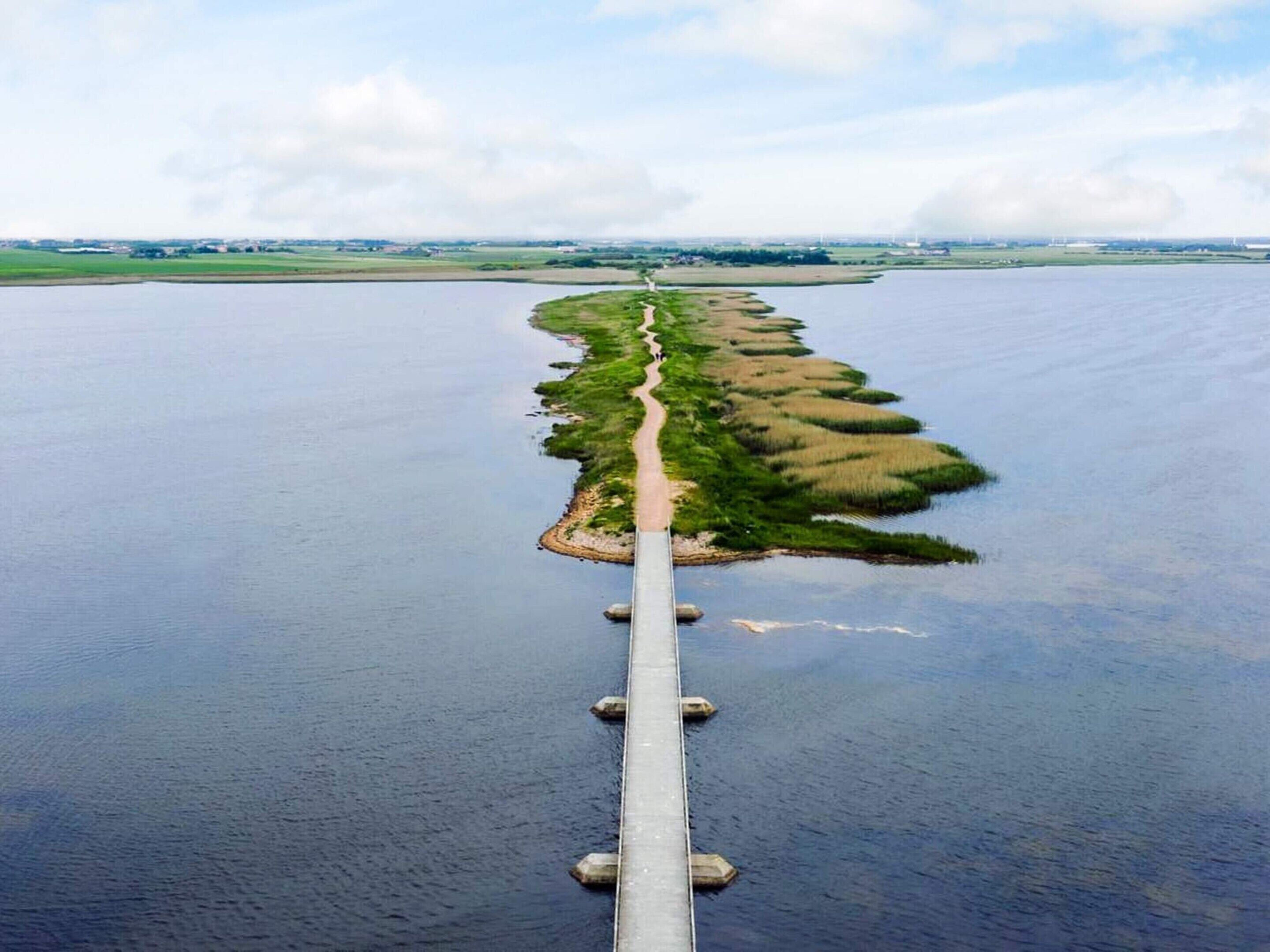 Un long pont étroit enjambant une étendue d’eau, avec un chemin qui longe sa longueur.