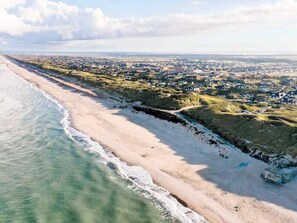 A coastal landscape with a beach, a town in the background, and a clear sky. - 4 Star Holiday Home in Ringkobing (Ringkobing)