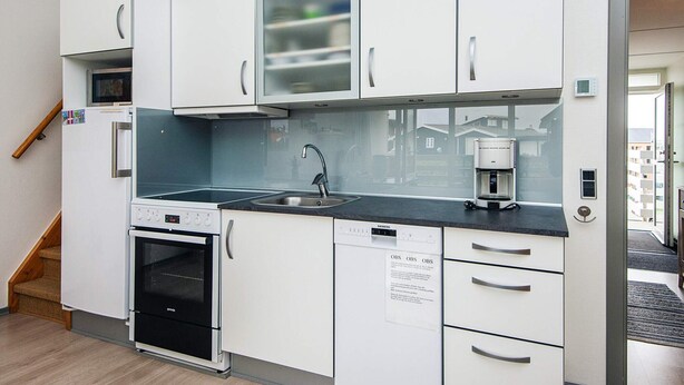 A compact kitchenette with white cabinets, a built-in oven, a coffee maker, and a microwave.