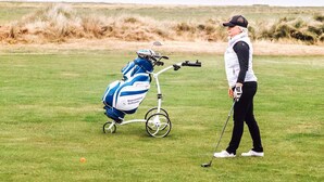 A person on a golf course with a golf bag and a golf club.