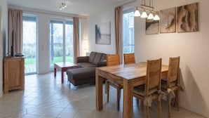 A spacious living room with a sofa, a dining table with chairs, and a large window with curtains. - Schone Ferienwohnungin Rechlin (Rechlin)