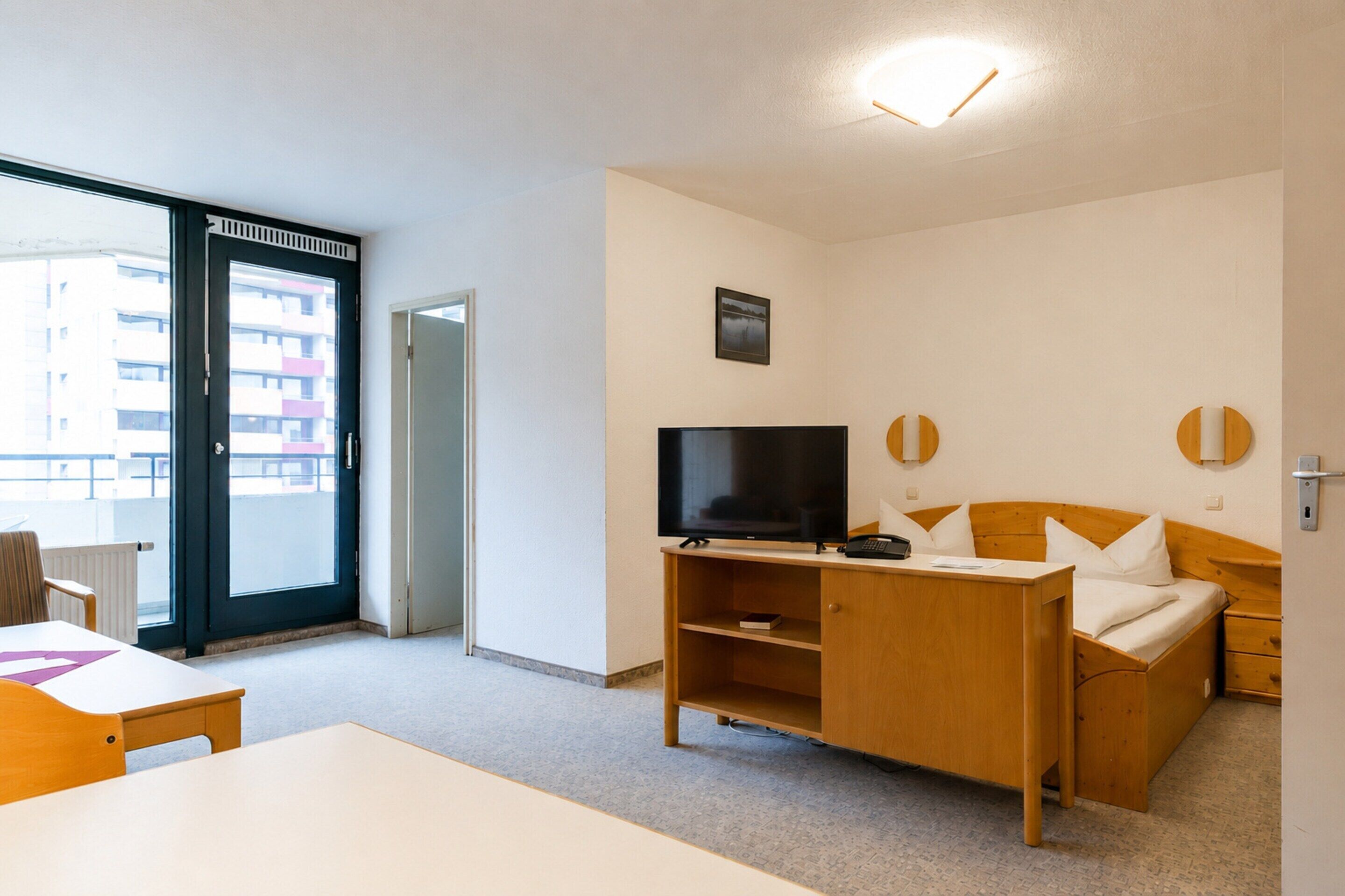 A hotel room with a bed, a TV, a desk, and a chair.
