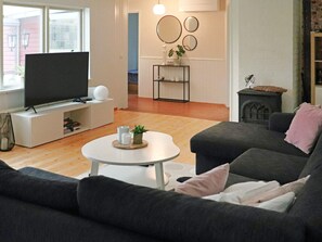 A living room with a flat-screen TV, a sofa, a coffee table, and a fireplace. - 4 Star Holiday Home in Mellbystrand (Mellbystrand)