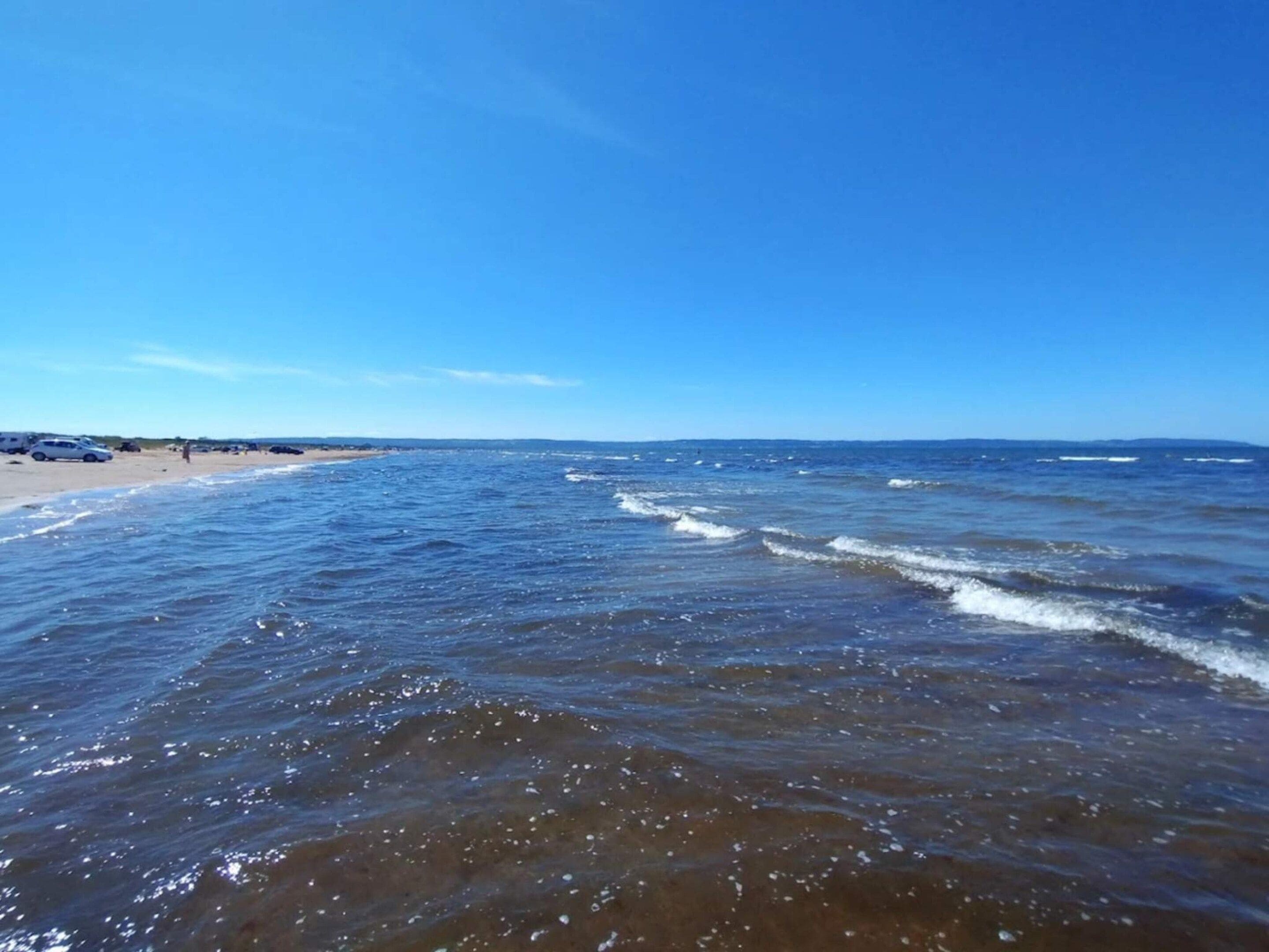A beach with clear blue water and a sandy shore.