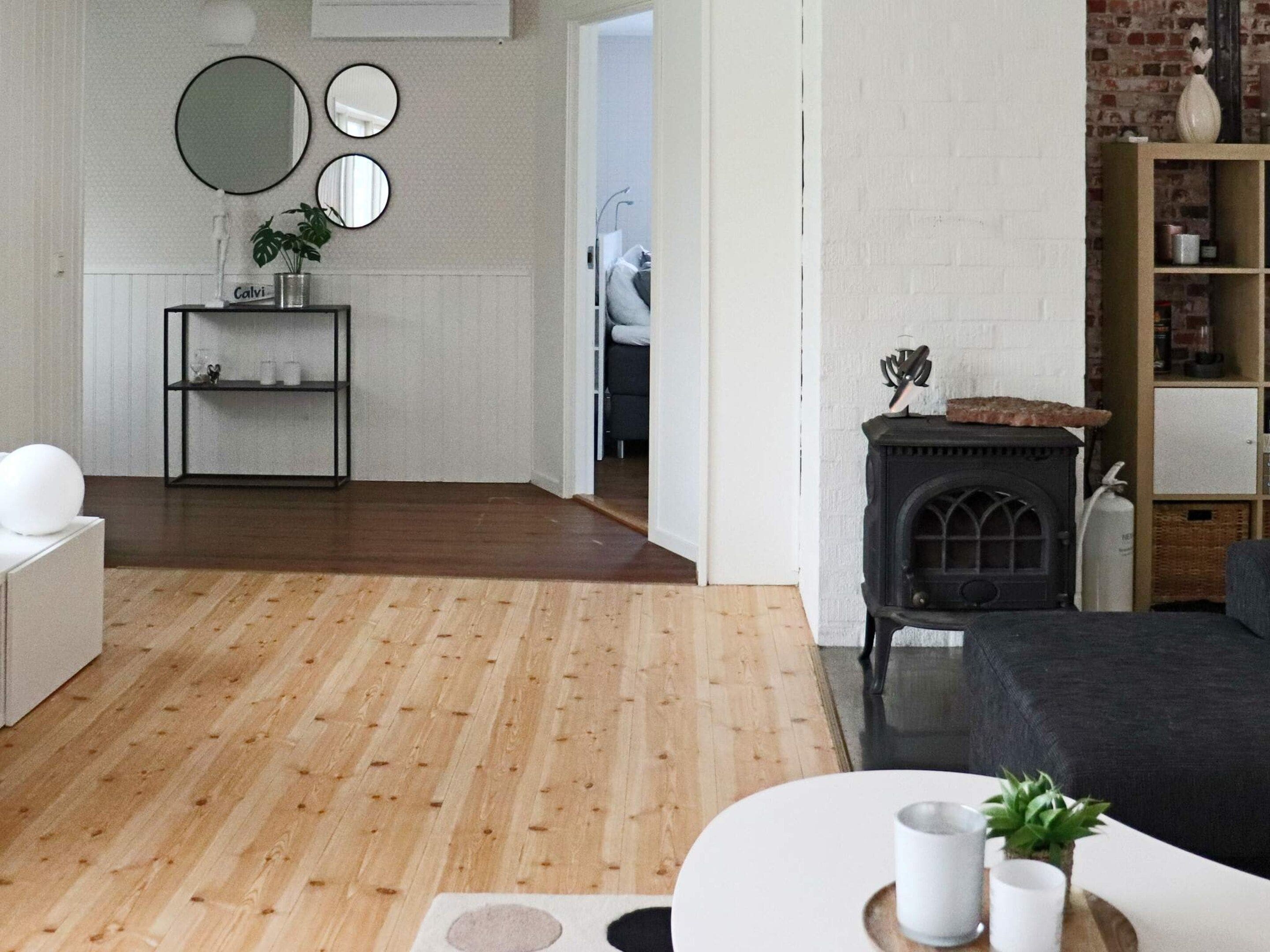 A modern living room with a fireplace, a coffee table with a plant, and a bookshelf.