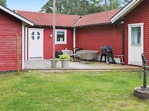 A red house with a tiled roof, a front door, a small porch with outdoor furniture, and a grill. - 4 Star Holiday Home in Mellbystrand (Mellbystrand)