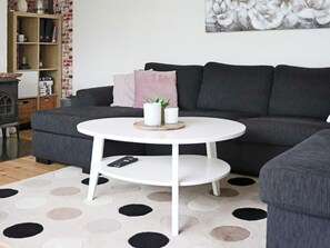 Una sala de estar moderna con un sofá gris, una mesa de centro blanca y una alfombra de lunares.