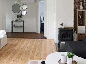 Una sala de estar moderna con piso de madera, un sofá negro, una mesa de centro blanca y una chimenea.