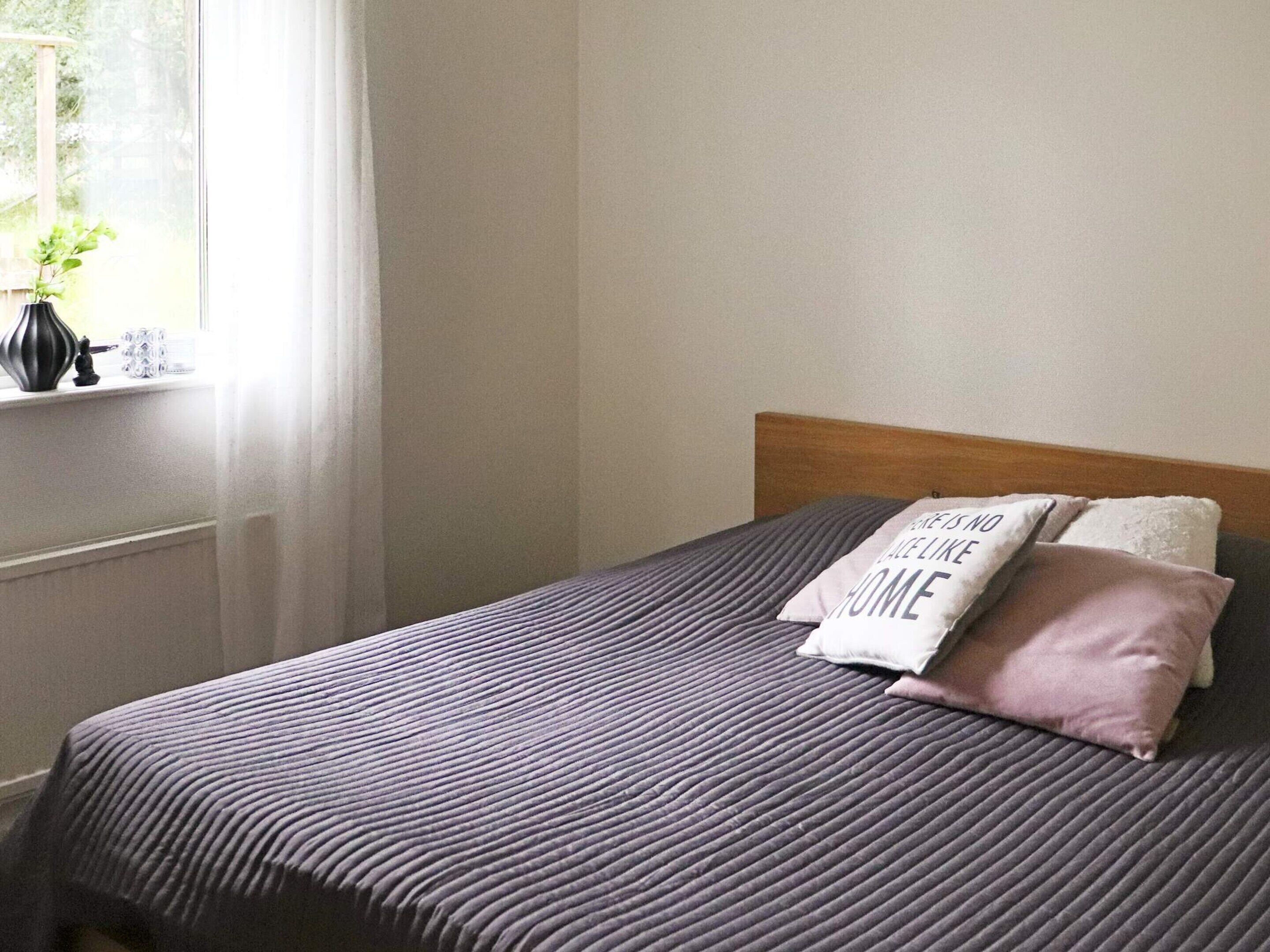 A neatly made bed with a striped bedspread and two pillows, one with text.