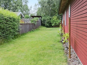 A red building with a wooden fence and a grassy yard. - 4 Star Holiday Home in Mellbystrand (Mellbystrand)