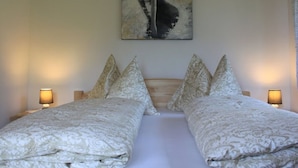 Una camera da letto con due letti, una testiera in legno, biancheria da letto fantasia e due abat-jour.