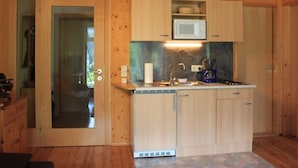 Una cucina compatta con mobili in legno, un forno a microonde, una macchina per il caffè e un lavandino.