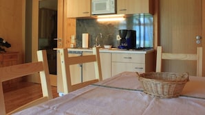 Una cucina compatta con mobili in legno, un forno a microonde, una macchina da caffè e un cesto di vimini sul tavolo.