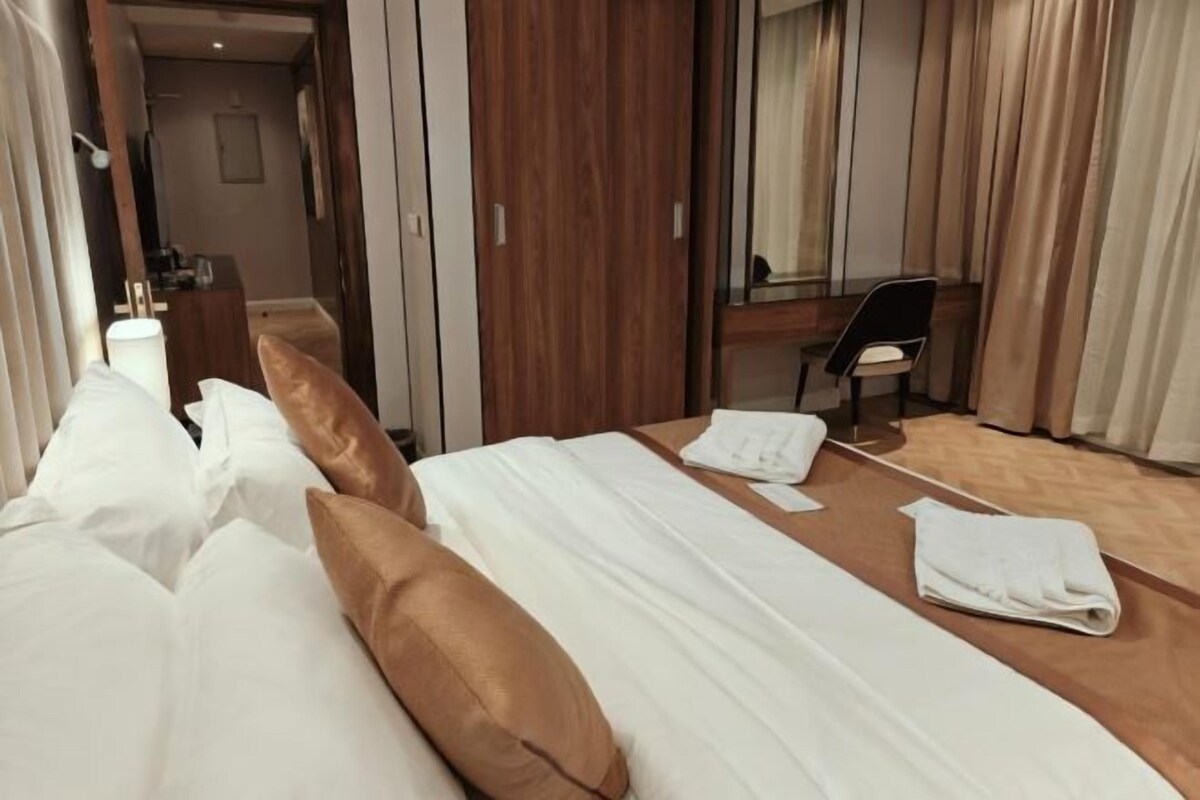 Une chambre d’hôtel avec deux lits, un bureau, une chaise et un miroir.