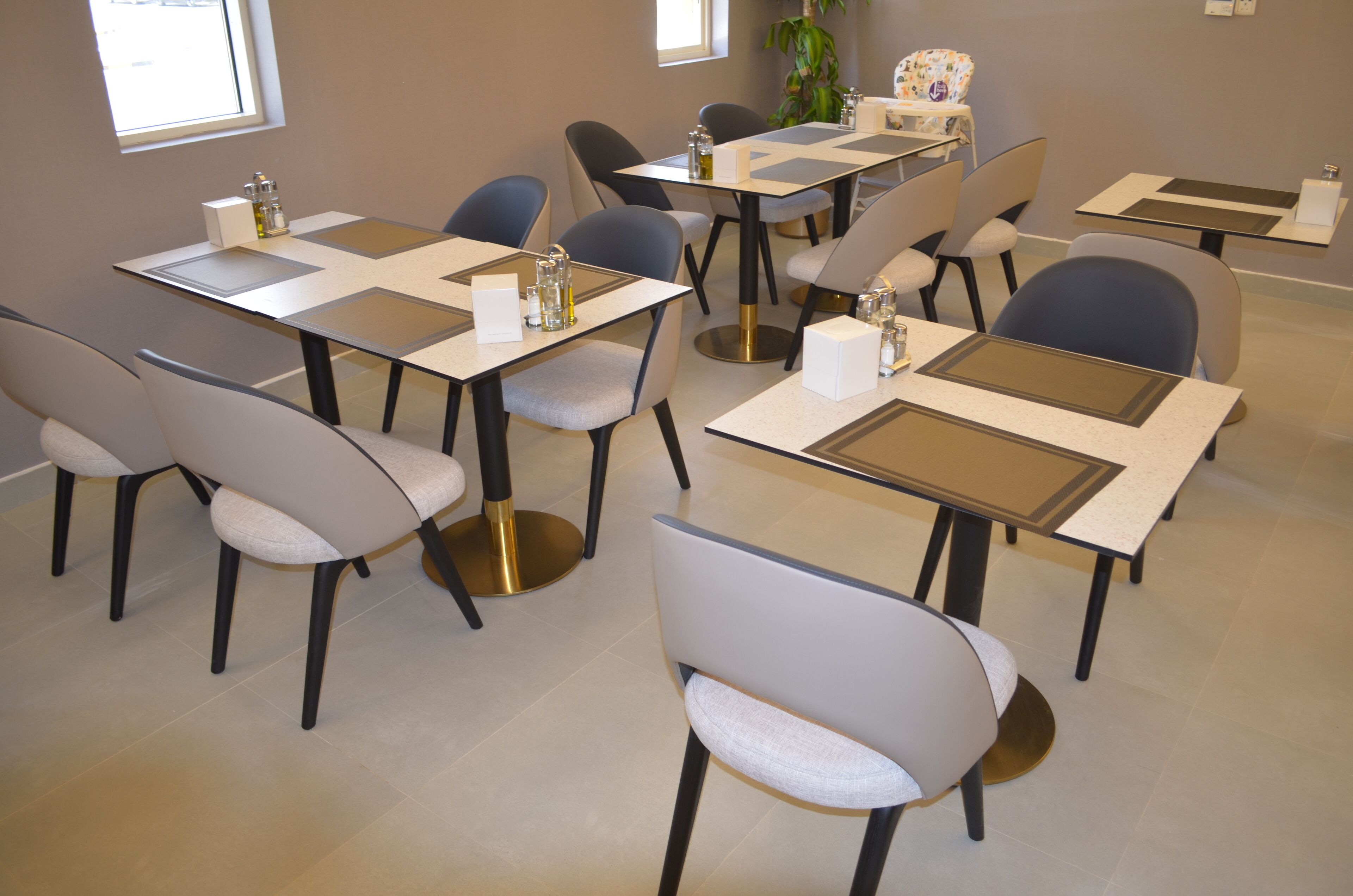 Een vergaderruimte met meerdere tafels en stoelen, voorzien van naambordjes en glazen.