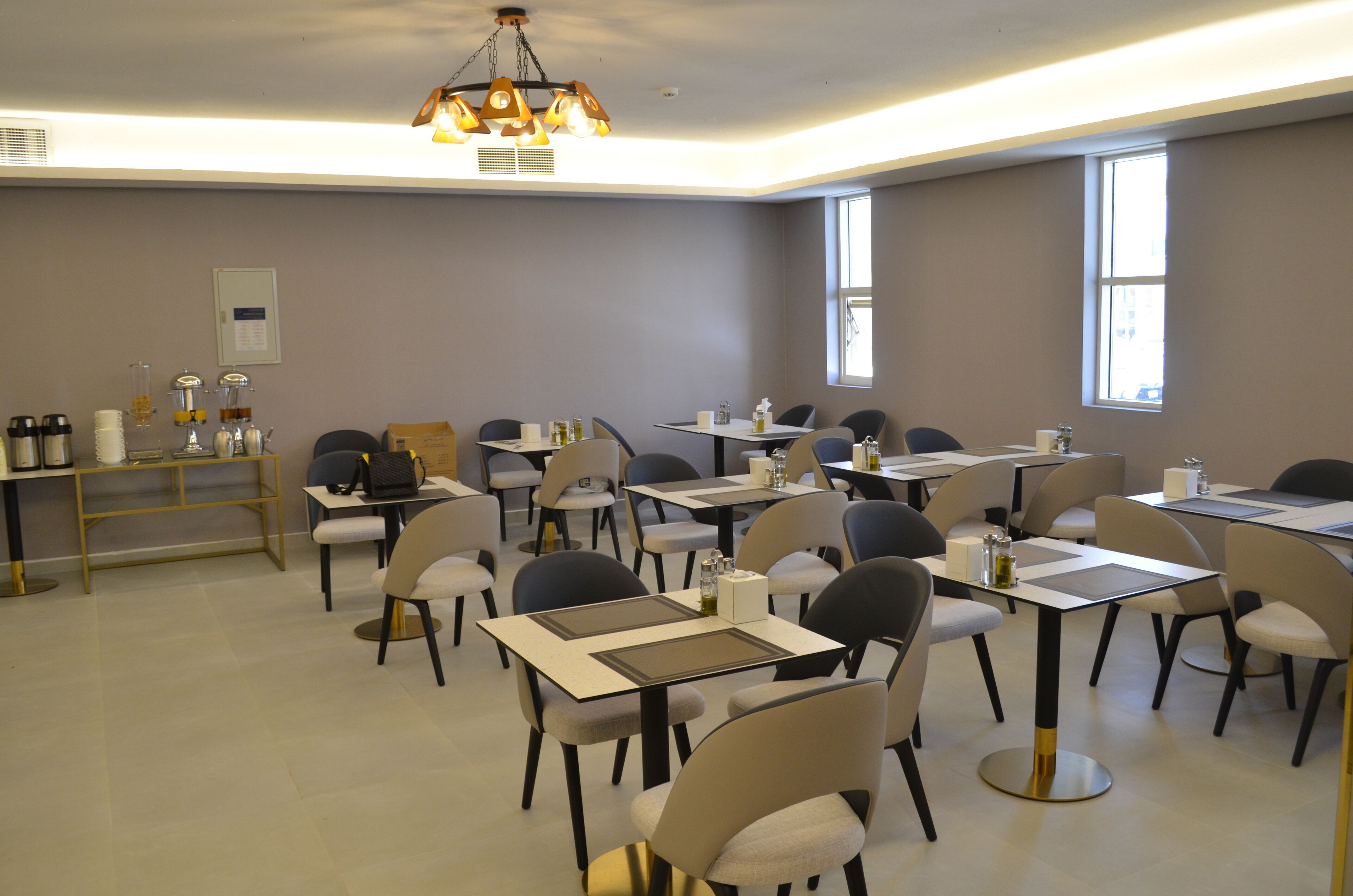 Une salle de conférence dotée de plusieurs tables et de chaises, équipée de plaques nominatives, de bouteilles d’eau et d’un coin café.