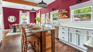 A kitchen with white cabinets, a wooden island, and pendant lighting. - The Pepper Place (Waco)