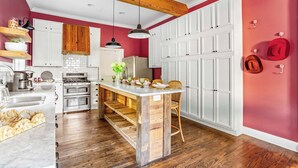 A kitchen with wooden beams, white cabinets, and a central island. - The Pepper Place (Waco)