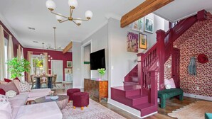A spacious living room with a staircase, a dining area, and a kitchen. - The Pepper Place (Waco)