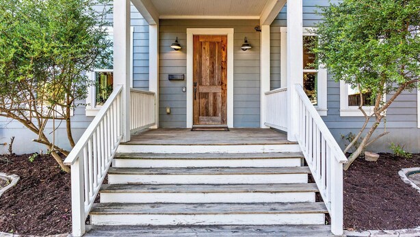 A house with a wooden front door, white railings, and a number '822' above the door. - The Pepper Place (Waco)