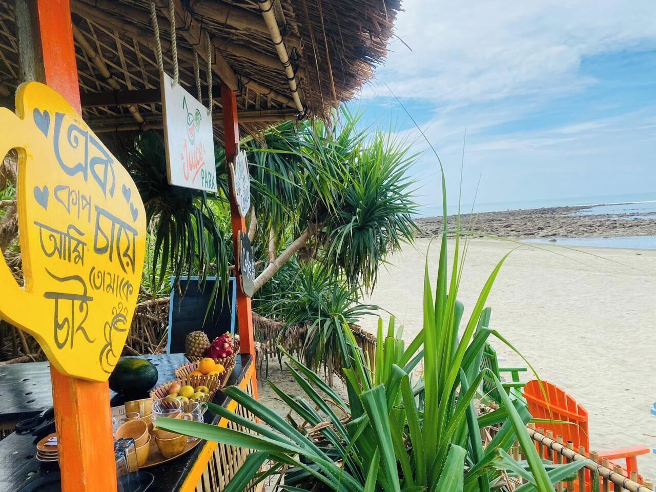 Un petit stand installé sur la plage, avec une enseigne et une structure surmontée d’un toit de chaume.