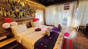 Een kamer met een bed, een 'Happy Anniversary' bord, ballonnen en een kat.
