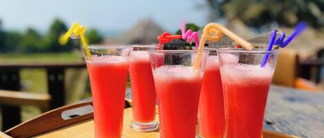 Four glasses of red beverage on a wooden tray.