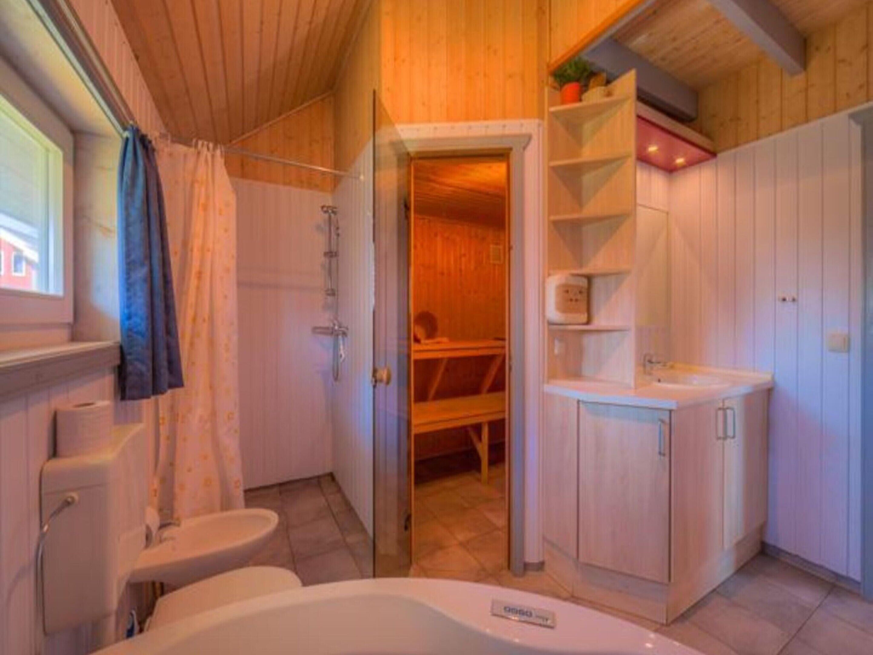 A wooden interior with a bathtub, a toilet, and a sink.