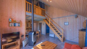 Un intérieur en bois avec une télévision, une cheminée et un escalier menant à un niveau supérieur.