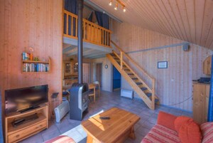 A wooden interior with a TV, fireplace, and a staircase leading to an upper level.