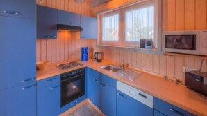Une cuisine de taille réduite avec des meubles bleus, une cuisinière, un four et un four à micro-ondes.