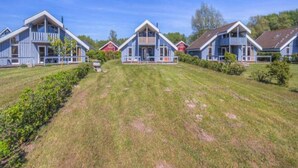 Une rangée de maisons bleues avec des bordures blanches et une pelouse verdoyante devant.
