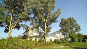 A two-story house with a balcony, surrounded by trees and a well-maintained lawn. - Elegant Eingerichtete Ferienwohnung (Mirow)