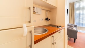 A modern kitchen with a wooden countertop, stainless steel sink, and hanging utensils. - Elegant Eingerichtete Ferienwohnung (Mirow)