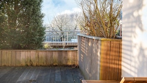 A wooden deck with a wooden fence and a view of a building in the background. - Elegant Eingerichtete Ferienwohnung (Mirow)