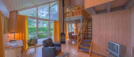 A spacious living area with a large window, a staircase, and a television.