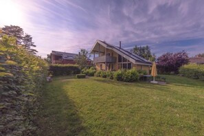 A house with a sloped roof, a balcony, and a well-maintained lawn. - Ferienhaus im Skandinavischen Stil (Mirow)