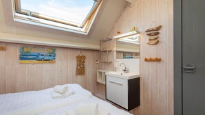A bedroom with two beds, a skylight, a bathroom with a sink, and wooden walls. - Studio in Zoutelande Near Stunning Beaches (Zoutelande)