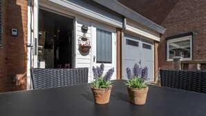 A patio with a black table and two potted lavender plants. - Studio in Zoutelande Near Stunning Beaches (Zoutelande)