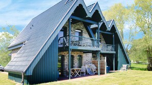 A chalet-style building with a steeply pitched roof, a balcony, and a small porch area with outdoor seating. - Doppelhaushalften Boltenhagen in Deutschland (Boltenhagen)