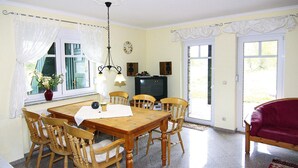A dining area with a wooden table and chairs, a television, and a red sofa. - Doppelhaushalften Boltenhagen in Deutschland (Boltenhagen)